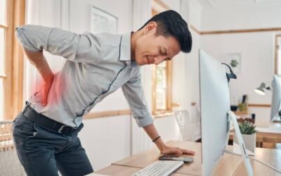 Person sitting at a desk with poor posture causing back pain