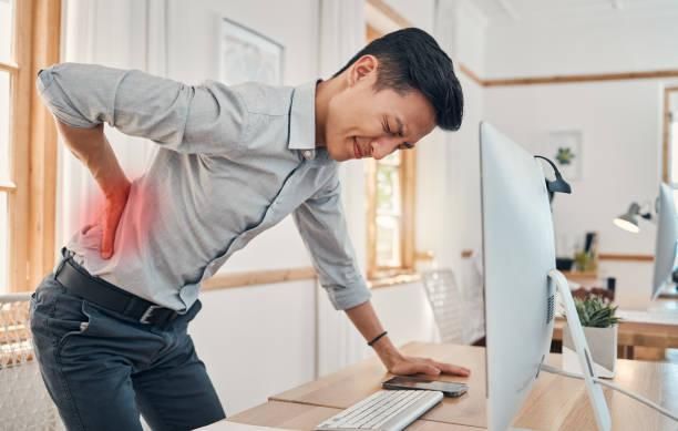 Person sitting at a desk with poor posture causing back pain